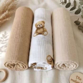 Kompozycja w stylu boho: trzy zwinięte w rulon otulacze z pofalowanego muślinu bawełnianego Double Gauze. Środkowa pielu