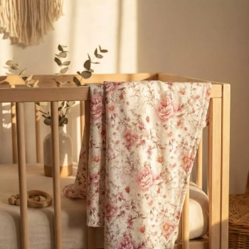 Kocyk niemowlęcy w różowe róże styl vintage przewieszony przez drewniane łóżeczko w pokoju boho