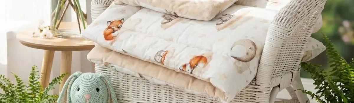 Kocyk z kolekcji Leśne Sny zaprezentowany w jasnym pokoju dziennym na wiklinowym fotelu, widoczne detale wykończenia.