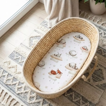Widok z góry na kosz Mojżesza z ubranym prześcieradłem 80x40 Leśne Sny, leżący na wzorzystym dywanie boho.