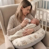 Mama karmiąca butelką noworodka przy użyciu beżowej poduszki do karmienia odciążającej kręgosłup.