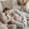 Mama czuwająca nad śpiącym noworodkiem w kokonie niemowlęcym Safari. Przytulna, domowa aranżacja sypialni.