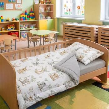 Sala przedszkola z niskimi łóżeczkami. Na pierwszym planie pościel z wypełnieniem Safari przygotowana do leżakowania.
