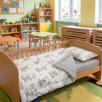 Sala żłobkowa z niskimi łóżeczkami. Na pierwszym planie pościel z wypełnieniem Safari przygotowana do leżakowania.