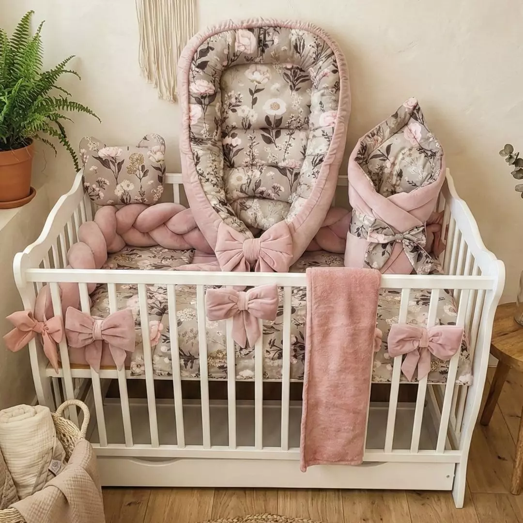 Kompletny, luksusowy zestaw do łóżeczka niemowlęcego z kolekcji Retro Bloom w jasnym pokoju w stylu boho. Kwiatowy kokon niemowlęcy, poduszka-miś oraz rożek.