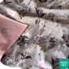 Zbliżenie na bawełniano-muślinowy kocyk niemowlęcy dla dziewczynki. Widoczny kwiatowy wzór Retro Bloom z peoniami, wywinięty spód z muślinu w kolorze brudnego różu oraz logo certyfikatu OEKO-TEX.