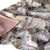 Zbliżenie na miękko ułożony, dwustronny letni kocyk niemowlęcy we wzór Retro Bloom. Szarobeżowa bawełna w botaniczny motyw z piwoniami i ciemnymi liśćmi oraz odwinięty róg z karbowanego muślinu w kolorze brudnego różu.
