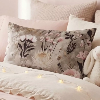 Prostokątna poduszka w botaniczny wzór w kwiaty Retro Bloom ułożona na łóżku oparta o inne, pastelowe poduszki. Na pierw