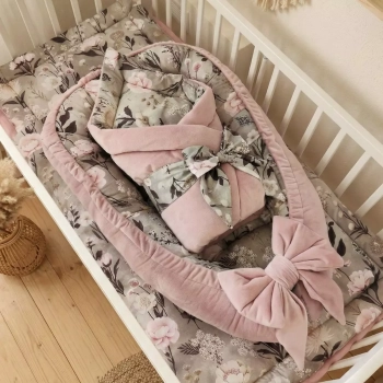 Wyprawka Retro Bloom z kokonem niemowlęcym, w którym leży wiązany rożek w kwiaty. Powyżej znajduje się płaska bawełniana